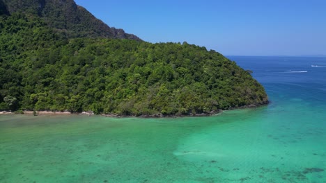 Turquoise-water-laps-gently-at-the-shore-of-a-tropical-island,-with-boats-dotting-the-seascape-and-lush-green-hills