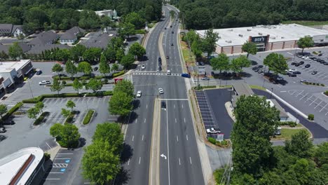 Toma-Aérea-Del-Tráfico-En-La-Autopista-Americana,-Con-Un-Centro-Comercial-Y-Una-Zona-De-Viviendas-Al-Otro-Lado-De-La-Calle.