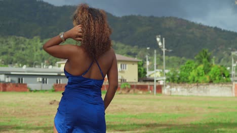 A-girl-with-curly-hair-in-a-short-blue-dress-enjoys-a-tropical-park-on-Trinidad's-Caribbean-island