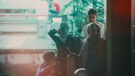 A-view-through-a-train-window-reveals-an-Arab-family-with-children-waiting-on-a-bustling-train-platform