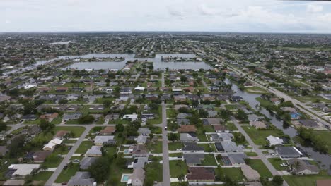 Aerial-view-of-a-suburban-neighborhood-with-houses-surrounding-interconnected-lakes,-showcasing-a-mix-of-greenery-and-water