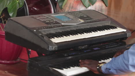 Musician-playing-an-electronic-keyboard-indoors-in-Kampala,-Uganda