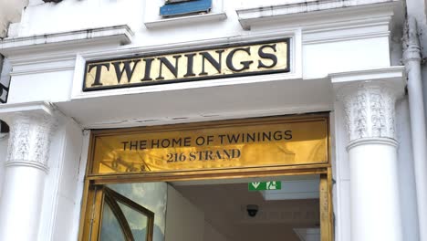 Exterior-De-La-Entrada-De-Twinings-A-Lo-Largo-De-La-Hebra-En-El-Templo-Con-Señalización-Visible-E-Interior-De-La-Tienda,-Londres,-Reino-Unido,-Julio-De-2023