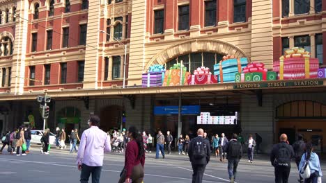 Daily-commuters-crossing-the-street-and-rushing-through-the-gate-at-Flinders-Street-Station-in-Melbourne-city-during-peak-hours,-busy-urban-life-in-the-city-center