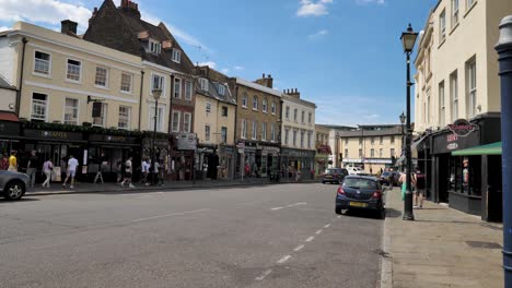 View-of-Greenwich-Church-Street-with-shops-and-pedestrians-along-the-road,-Greenwich,-London,-UK,-July-2023