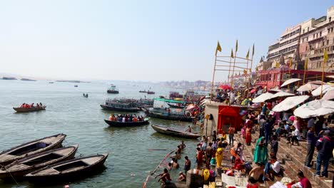 Das-Ufer-Des-Heiligen-Flusses-Ganges-Ist-Tagsüber-Voller-Gläubiger-Und-Traditioneller-Holzboote.-Video-Aufgenommen-Am-Dashashwamedh-Ghat-In-Varanasi,-Uttar-Pradesh,-Indien,-08.-März-2024