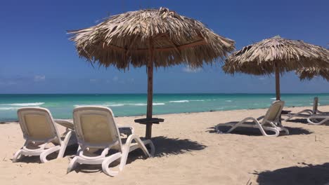 Playa-De-Arena-Y-Sombrillas-De-Paja-En-Varadero,-Cuba-Con-Tumbonas-Y-Océano-Azul