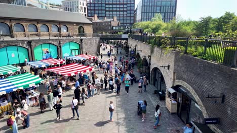 Vibrant-Saturday-market-at-Coal-Drops-Yard-in-Kings-Cross,-London-with-many-people-browsing-stalls