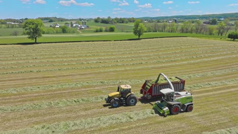 Ein-Claas-Traktoren-Arbeiten-In-Harmonie,-Pressen-Heu,-Wenn-Der-Tag-Zu-Ende-Geht,-Und-Verwandeln-Felder-In-Ordentlich-Organisierte-Linien-Unter-Azurblauem-Himmel