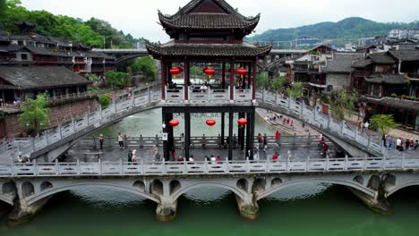 Tourists-visit-famous-Snow-Bridge-over-Tuo-Jiang,-Phoenix-Ancient-Town