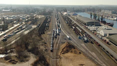 Panning-drone-shot-of-a-train-transporting-cargo-near-a-port-shore