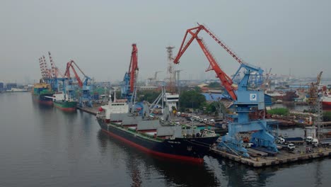 Grúas-Portuarias-Rojas-Y-Contenedores-De-Carga-Atracan-En-El-Puerto-De-Tanjung-Priok