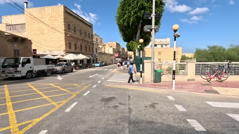 Walking-along-the-streets-of-Malta-on-a-sunny-day,-navigating-walkways-and-pedestrian-areas-with-ships-and-street-traffic