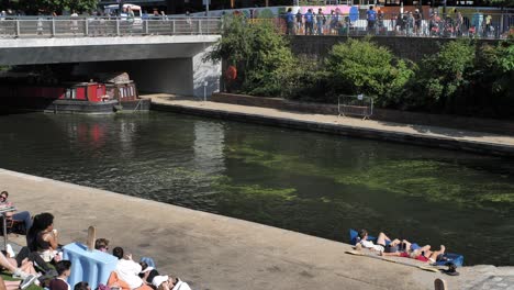 Public-enjoying-outdoor-cinema-at-Regent's-Canal-Green-Steps-along-the-Towpath,-King's-Cross,-London,-UK,-July-2023