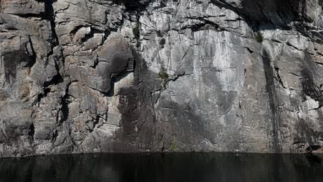 Drohnenaufnahmen-Folgen-Einem-Schlauchboot,-Das-Sich-Langsam-Einer-Hoch-Aufragenden-Bergwand-In-Einem-Fjord-Nähert