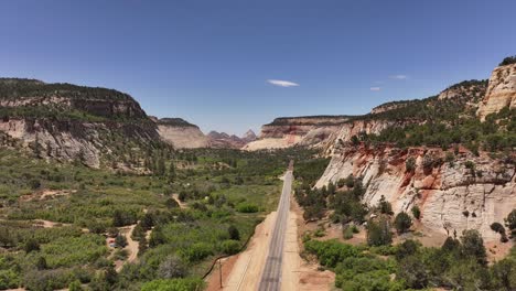 Dramatic-desert-road-through-lush-valley-framed-by-cliffs-in-Zion-National-Park,-Utah-USA