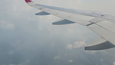 Many-clouds-are-moving-around-from-the-window-of-the-plane-and-a-big-city-is-visible-below