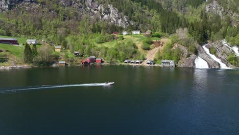 Tourists-on-guided-boat-tour-arrive-at-spectacular-triple-waterfall-Tysseknappen-in-Norway,-aerial-reveal