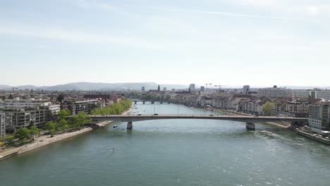 Aerial-view-overlooking-a-bridge-crossing-the-river-in-Basel,-Switzerland,-capturing-the-blend-of-urban-infrastructure-with-natural-surroundings,-symbolizing-modern-connectivity-and-scenic-tranquility