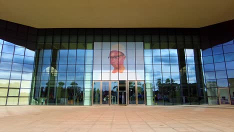 Vista-Frontal-Caminando-Del-Retrato-De-Sir-DK-Jaara-En-La-Entrada-Del-Centro-Internacional-De-Conferencias-Sdkj-En-Banjul.