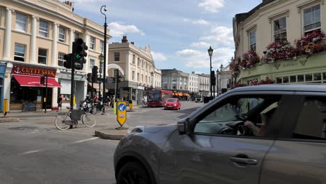 Traffic-and-pedestrians-on-Greenwich-Church-Street,-showcasing-the-busy-high-street-in-Greenwich,-London,-UK,-July-2023