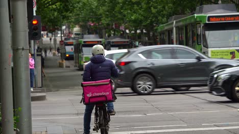 Busy-traffic-on-the-Swanston-streets-in-downtown-Melbourne-bustling's-central-business-district-with-pedestrians-crossing-and,-cars-and-buses-driving-along-the-street,-hustle-and-bustle-of-urban-life