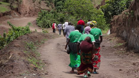 Gente-Caminando-En-Fila-A-Lo-Largo-De-Un-Camino-De-Tierra-Rodeado-De-Exuberante-Vegetación-En-Kampala,-Uganda