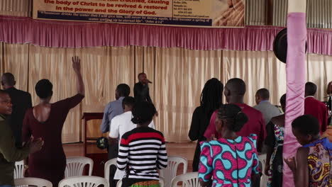 Pastor-Africano-Negro-Cantando-En-El-Escenario-De-Una-Iglesia-Cristiana-De-Misión-De-Carro-Evangelista-Mientras-La-Gente-Baila-Y-Canta-Para-Dios