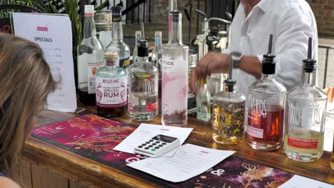 Woman-buying-an-alcoholic-drink-in-Canopy-Market,-King's-Cross,-London,-UK,-July-2023