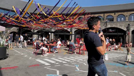 Public-enjoying-the-courtyard-of-Coal-Drops-Yard,-King's-Cross,-London,-UK,-July-2023