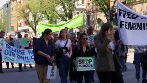 Protesters-march-for-environmental-justice-in-Stockholm,-Sweden,-holding-signs-and-banners