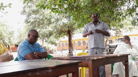 African-Man-Speaking-With-Other-Man-And-Priest-Listening-In-Ugandan-School-Campus