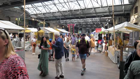 People-exploring-various-vendor-stalls-inside-Canopy-Market-under-a-covered-space,-King's-Cross,-London,-UK,-July-2023