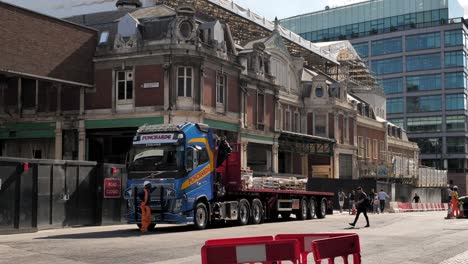 Exterior-view-of-the-restoration-and-redevelopment-of-Smithfield-Market-with-construction-vehicles-and-workers,-Farringdon,-London,-UK,-July-2023