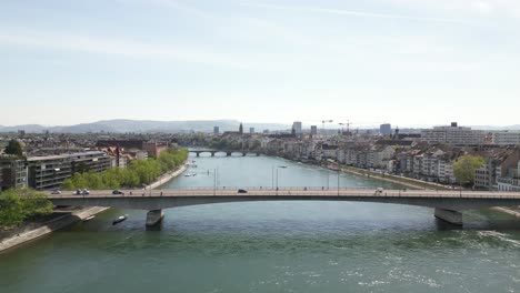 Aerial-of-a-bridge-spanning-Basel's-river,-showcases-the-harmonious-blend-of-cityscape-and-natural-beauty,-epitomizing-connectivity-and-tranquil-scenery