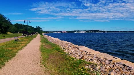 A-wall-running-along-Casco-Bay-walking-trail-with-buildings-on-far-shore-Portland,-Maine