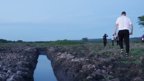 Männlicher-Tourist-überquert-Kanal-In-Ländlicher-Landschaft-In-Uganda