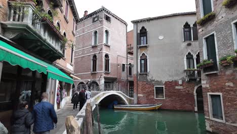 Travelers-and-visitors-cross-Venice's-stone-bridge,-Ponte-del-Piovan,-connecting-with-the-city's-historic-charm-and-picturesque-waterways