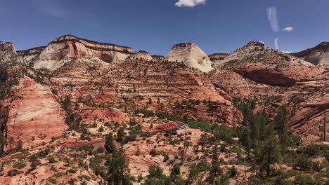 Zion-National-Park's-rugged-red-rock-formations-under-a-clear-blue-sky,-showcasing-unique-geological-features-and-sparse-vegetation,-Utah,-USA