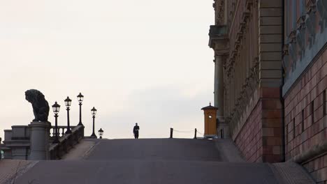 Silhouette-of-Royal-Guard-marching-by-Stockholm-Palace,-distance-view