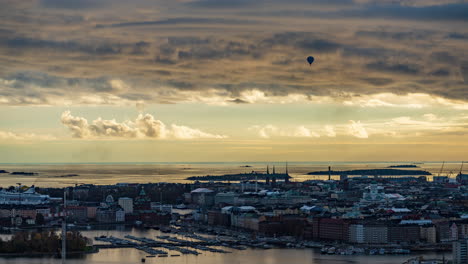 Zeitraffer-Eines-Heißluftballons-Und-Wolken,-Die-über-Die-Skyline-Von-Helsinki-Ziehen,-Sonnenuntergang