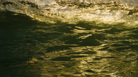 Surface-of-ocean-water-glistens-from-sunrise-light-rays-behind-back-with-dreamy-liquid-pattern