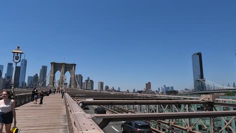 Schwenkaufnahme-Mehrerer-Menschen,-Die-über-Die-Brooklyn-Bridge-Gehen,-Und-Autos,-Die-Auf-Der-Unteren-Ebene-Auf-Der-Strecke-über-Die-Brooklyn-Bridge-Fahren