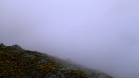 Aerial-view-flying-over-a-mountain-ridge-disappearing-into-white-out-conditions