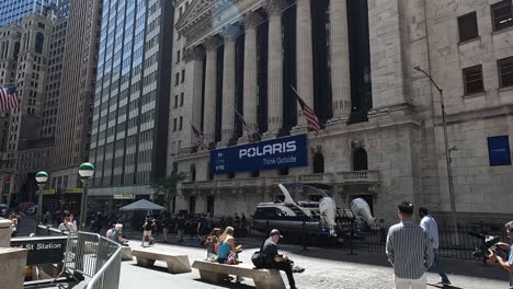 Panning-shot-of-the-New-York-Stock-Exchange-building-with-an-Asian-man-posing-to-the-camera,-a-yacht-parked-in-front-of-the-NY-exchange