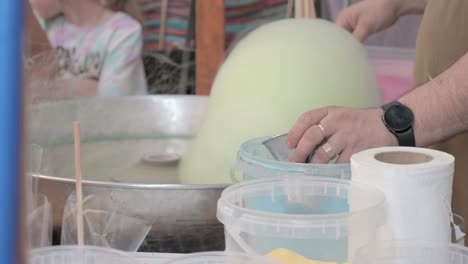 Close-up-of-a-man-spinning-yellow-cotton-candy-at-a-fair