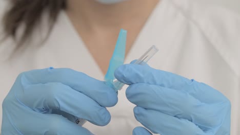 Close-up-of-a-healthcare-worker-with-gloves-putting-a-needle-into-a-syringe