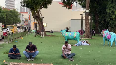 Foreign-workers-resting-on-a-grass-patch-in-Little-India,-Singapore