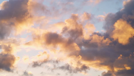 Nubes-Suaves-Y-Esponjosas-Que-Se-Mueven-Rápidamente-Brillan-En-Rosa-Y-Rojo-Contra-El-Cielo-Azul-Al-Atardecer,-Impresionante-Fondo-Natural-En-Un-Día-Ventoso