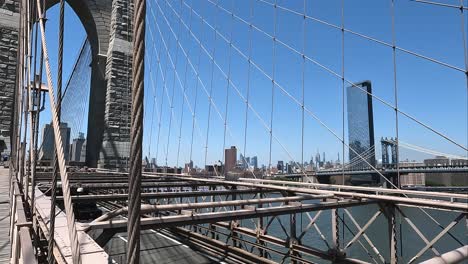 Asian-and-Afro-American-women-walk-on-the-Brooklyn-Bridge-in-slow-motion-while-cars-drive-lower-level-of-the-bridge